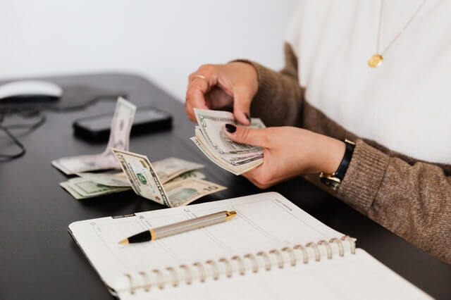 Bookkeeping Services crop payroll clerk counting money while sitting at table
