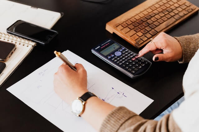 Bookkeeping Services crop woman using calculator and taking notes on paper