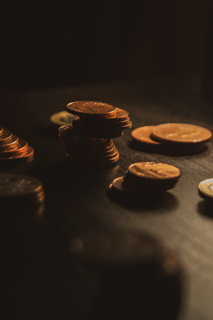 Home Close-up of a stack of bronze coins on a wooden surface in dim lighting.